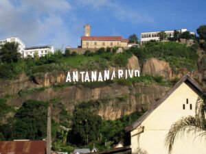 14-Day Best of Northeastern Madagascar Safari Adventure A view of Antananarivo, Madagascar, with the city's name displayed on a rocky hillside, buildings perched atop the hill, and a tan house in the foreground.